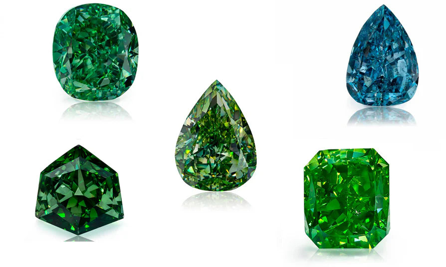 A selection of five vibrant fancy-colored diamonds in shades of green and blue, each cut in a different shape including cushion, pear, pentagon, radiant, and modified brilliant, all displayed on a reflective white surface to highlight their vivid color and brilliance.
