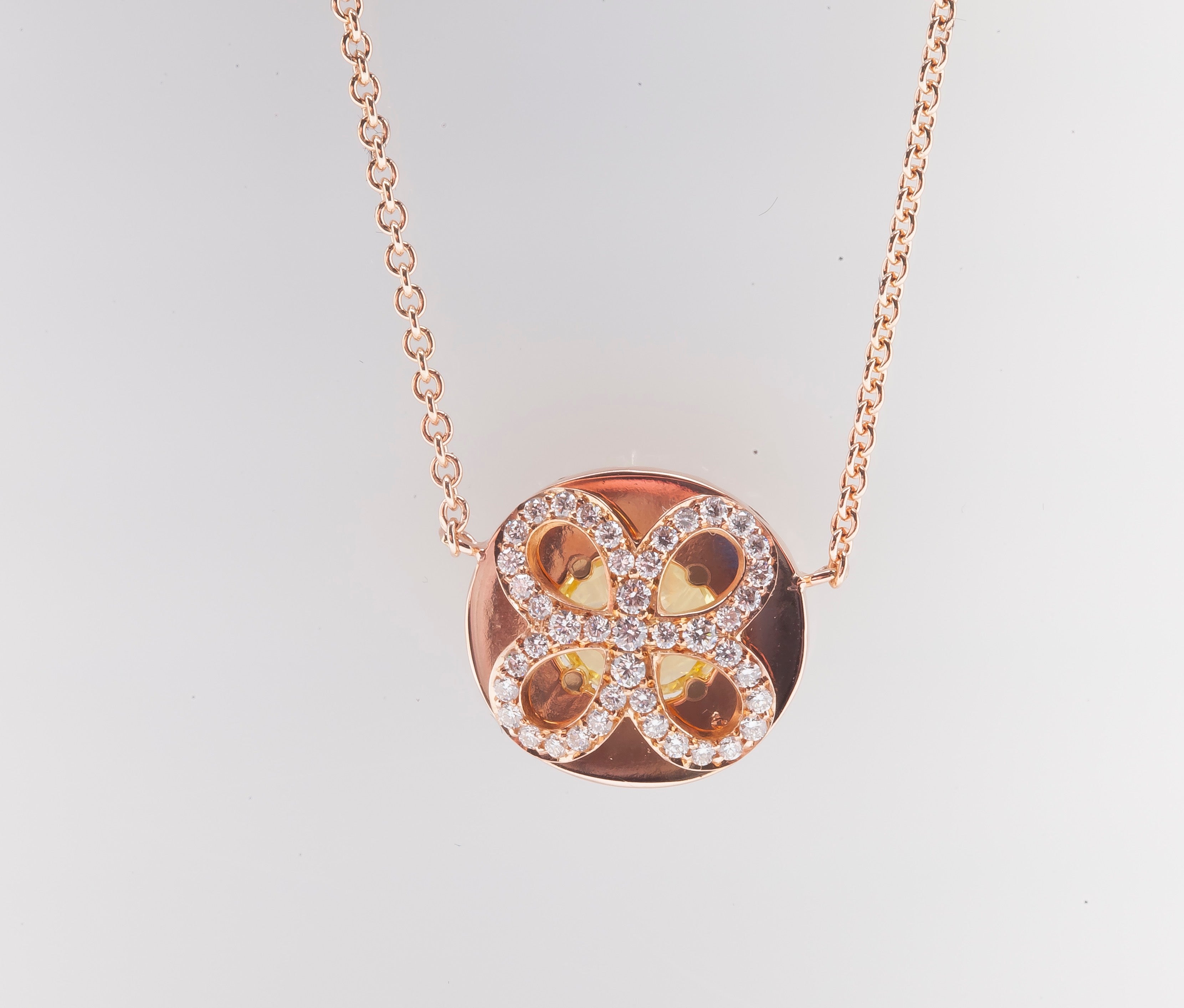 Four-leaf clover pendant with colorless melee diamonds and hollow middle to see the yellow diamond from the other facet